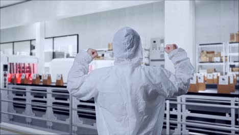back view of asian male scientist celebrating the succeed while standing with conveyor for packaging coffee beans in bags at coffee factory