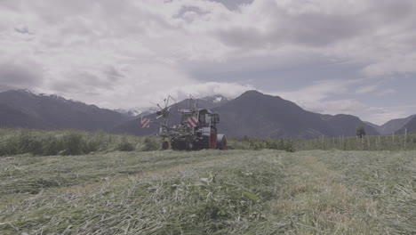 tractor mowing grass on field, alpine meadow countryside , dolomites