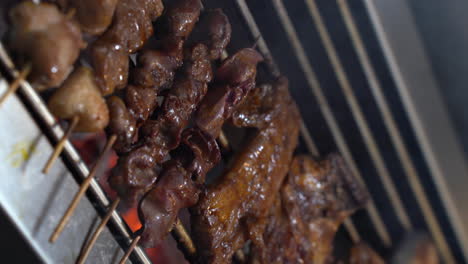 vertical shot of person turning barbeque skewers on griller. - close up
