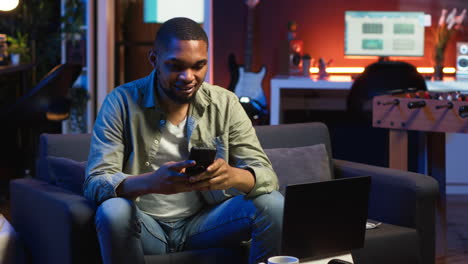 vertical video chill self employed guy enjoying a break with his mobile phone on sofa
