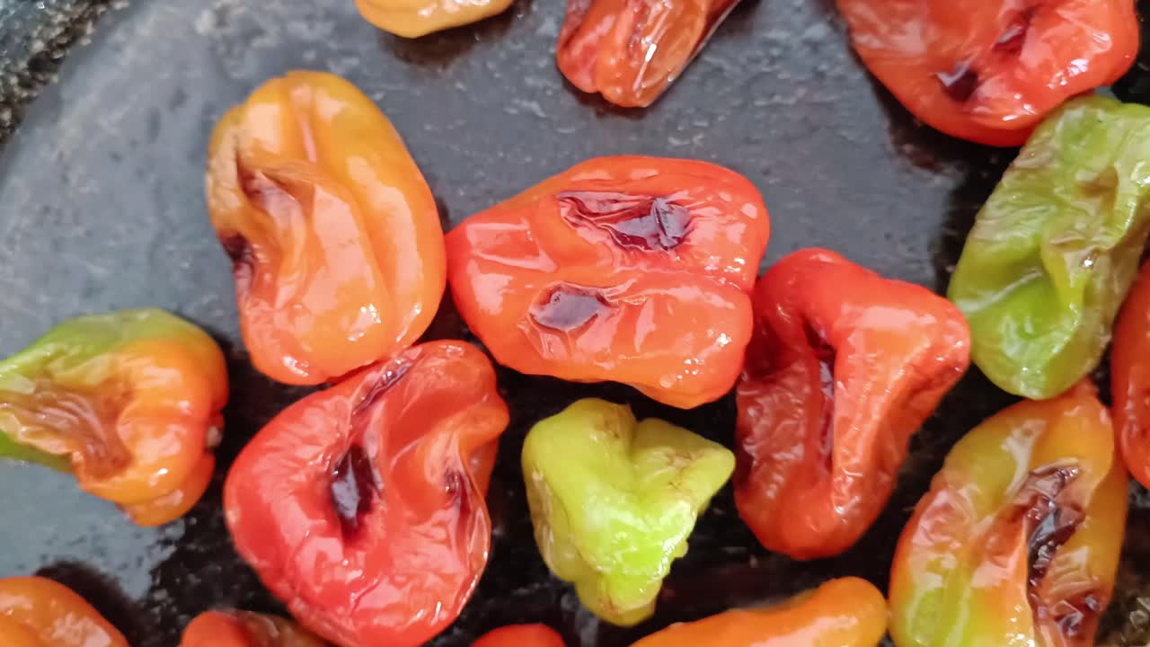 Colorful habanero chiles roasting on hot surface in close up view