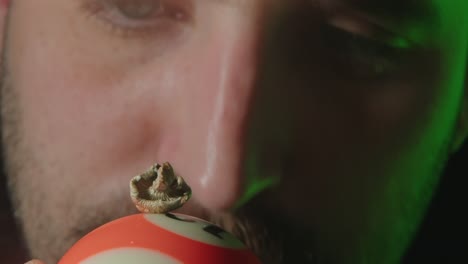 an individual is carefully examining the psilocybin mushroom positioned atop the billiard ball