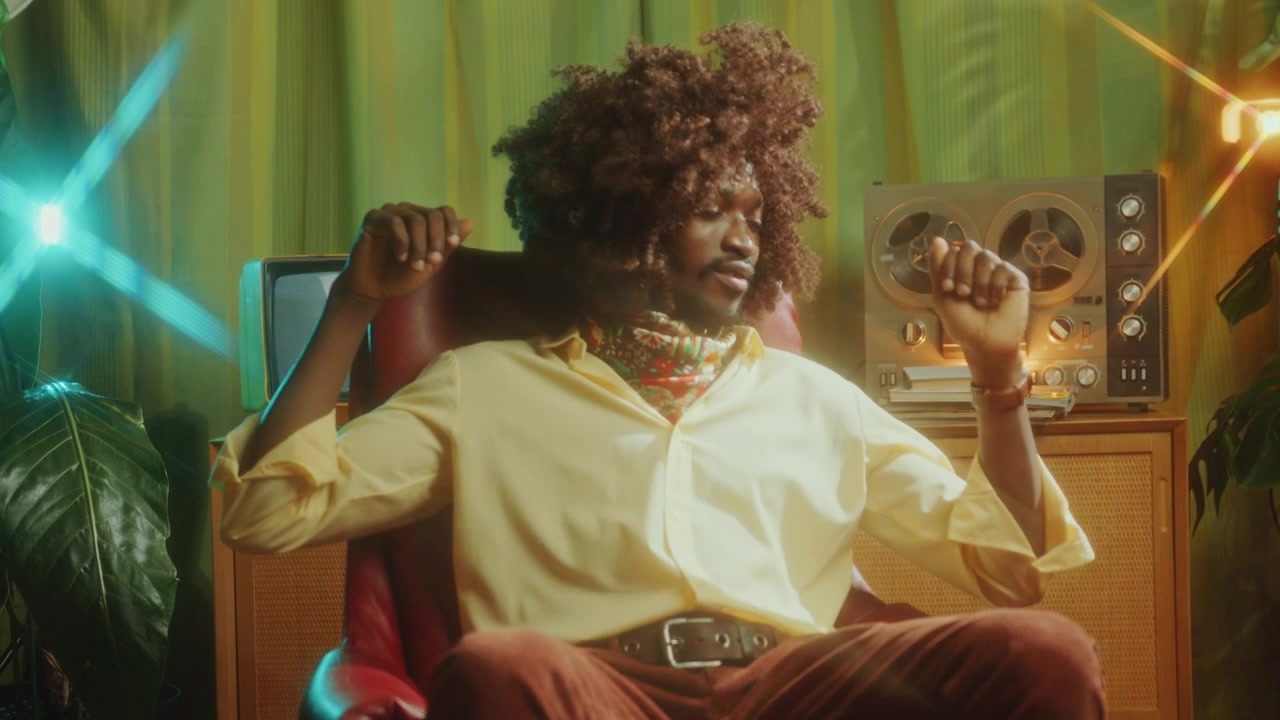 Afroamerikansk mand sidder i retrostudie og danser til musik