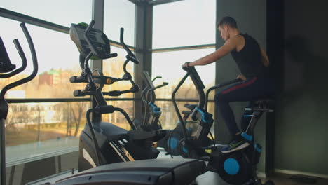 Hombres-Jóvenes-Activos-Haciendo-Girar-Una-Bicicleta-De-Aire-En-El-Gimnasio-Con-Entrenadores.-Entrenamiento-Masculino-En-Bicicleta-De-Aire.