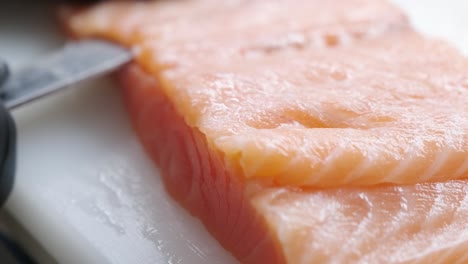 el cocinero corta el pescado rojo con un cuchillo.