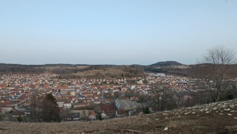 Timelapse-from-day-to-night-of-a-city-with-traffic-from-a-wide-hill-sided-point-of-view-at-a-clear-blue-sky-evening