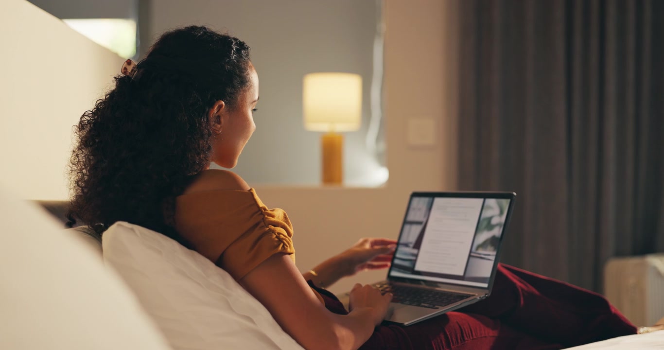 Young Woman Working on Laptop While Relaxing in Bed