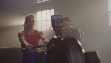 woman working out on a rowing machine with personal trainer