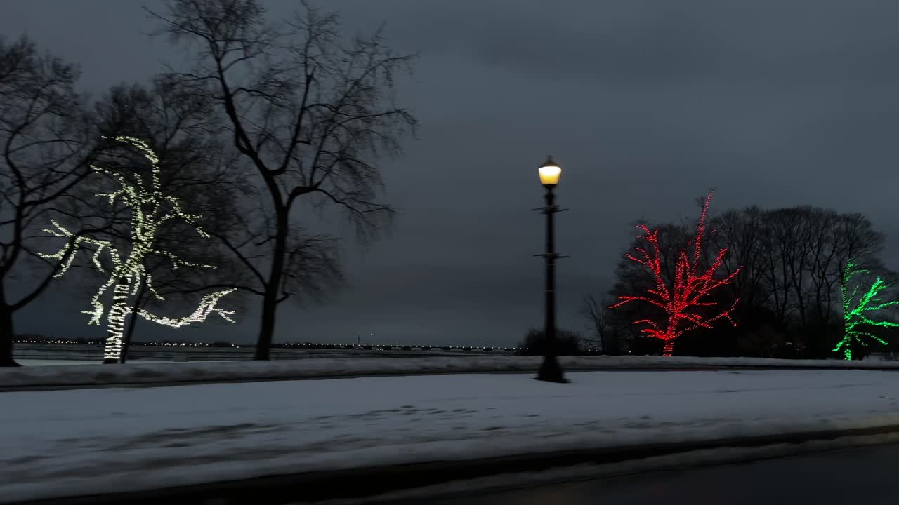 눈 덮인 길을 따라 저녁 동안 크리스마스 조명으로 싸인 겨울 나무