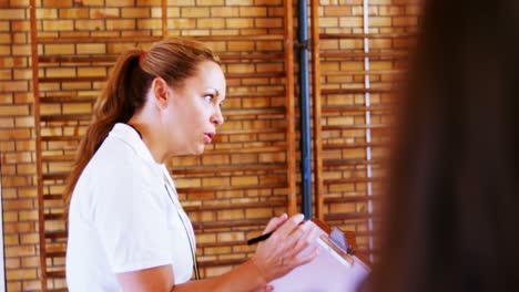 Female-coach-instructing-school-students-in-basketball-court