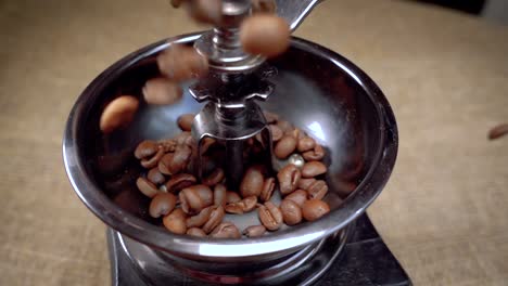 los granos de café caen en el viejo molinillo. cámara lenta con seguimiento de rotación.