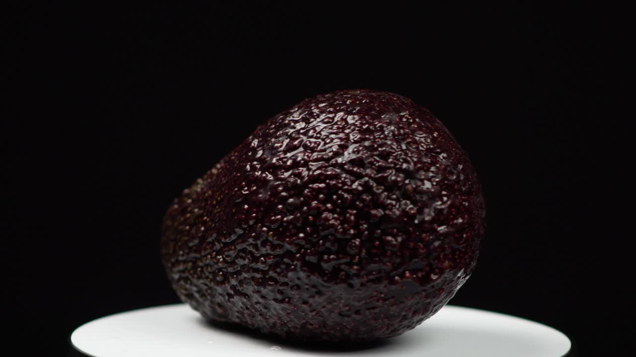 close up de todo el aguacate brillante girando sobre un fondo negro
