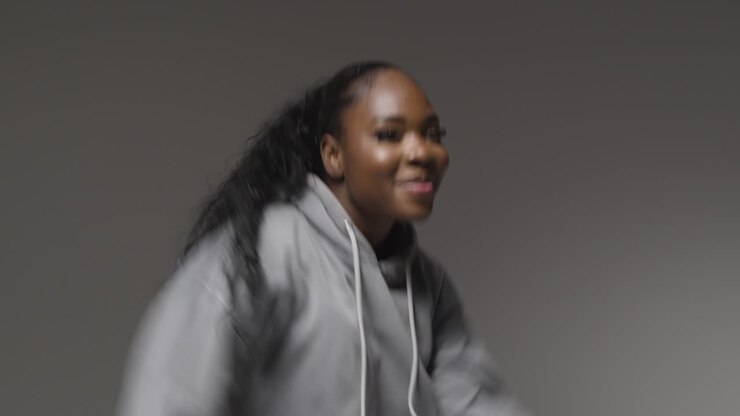 Studio Portrait Shot Of Young Woman Wearing Hoodie Dancing With Low Key Lighting Against Grey Background 6