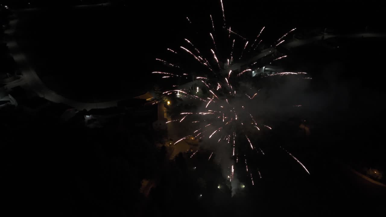 Fireworks display lighting up the dark sky over a city with distant glowing lights.