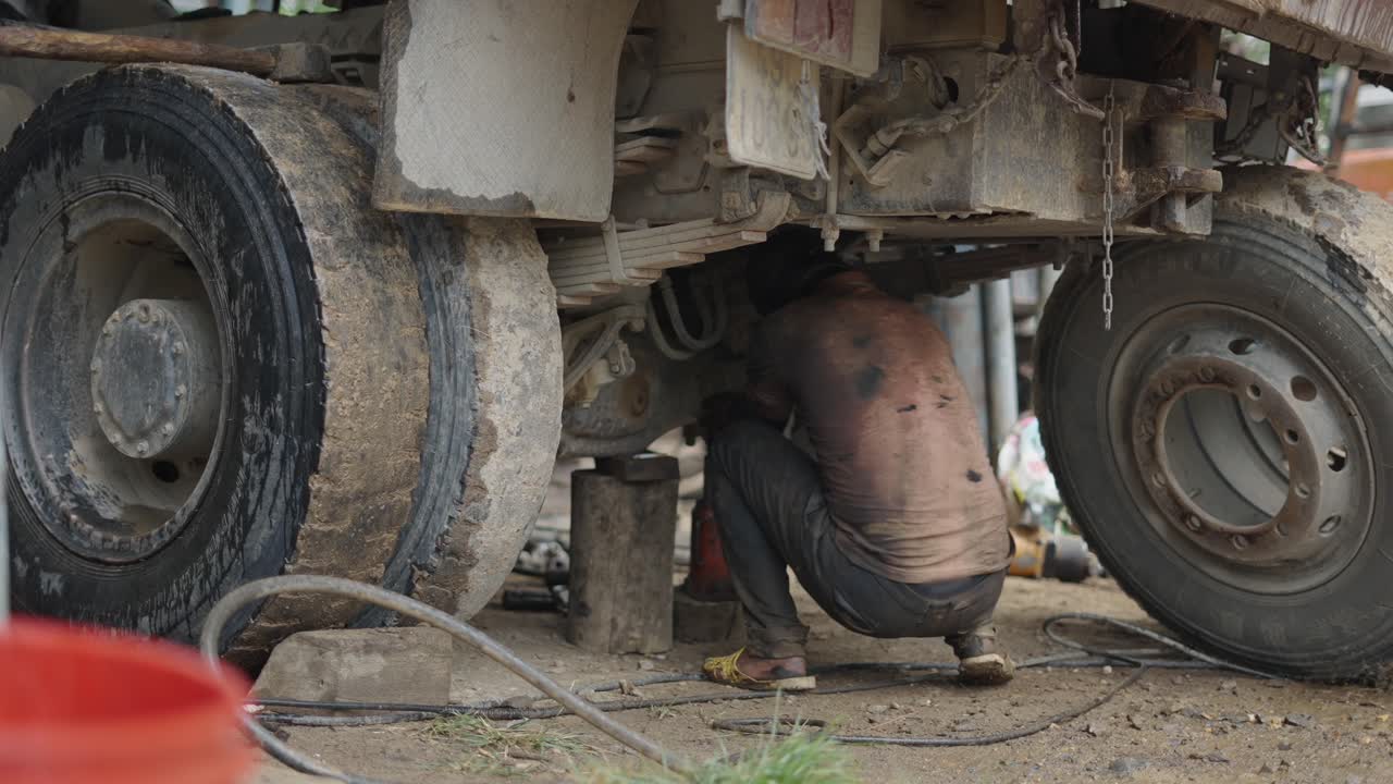Truck Mechanic Working on a Heavy Duty Vehicle Undercarriage