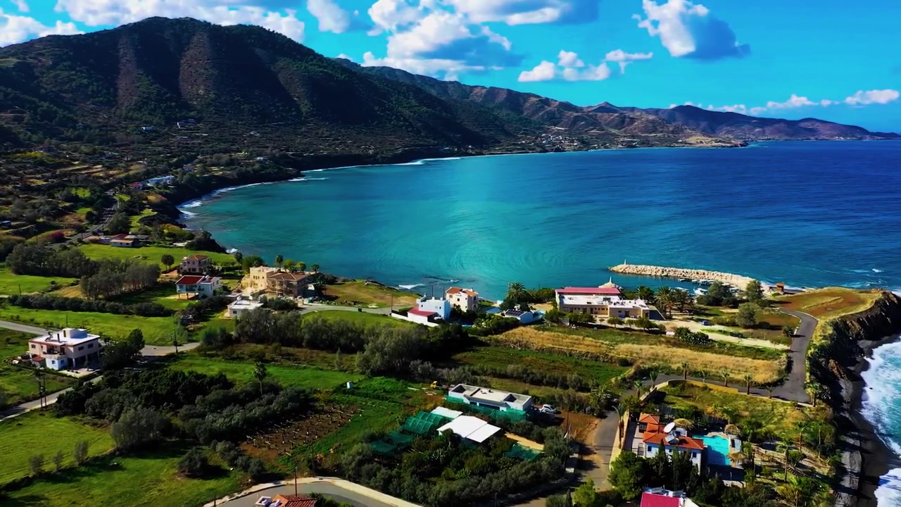 Cadeias de montanhas escarpadas observam as águas do Mediterrâneo e casas rurais ao longo de uma costa rochosa