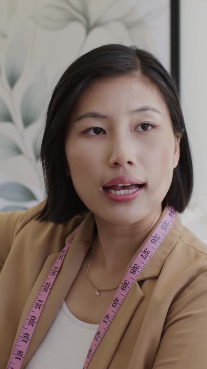 Video verticale: Designer donna con metro a nastro che prende un abito con perline, ispezionandolo con una collega più anziana per la vestibilità
