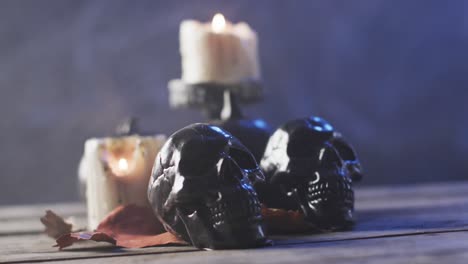 Video-of-halloween-skulls,-candles-and-smoke-with-copy-space-on-purple-background