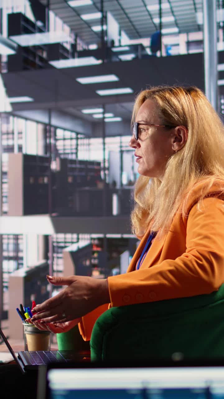 Professionista donna che parla e gesticola durante una videochiamata in un ufficio moderno.