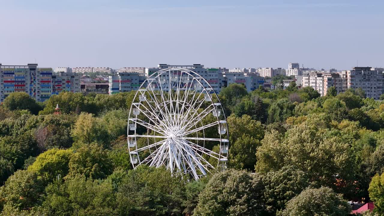 Rotating Drone View of a Ferris Wheel in Oraselul Copiilor Park with Apartment Buildings in the Background, Bucharest, Romania
