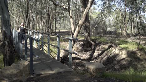 mujer rubia caminando hacia la cámara en la naturaleza en el puente