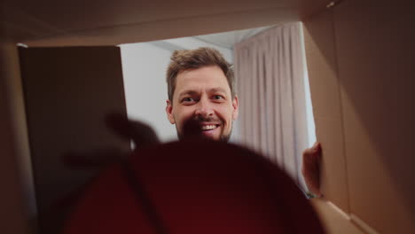 happy young man shopper unpacking cardboard box delivery parcel online shopping purchase at home