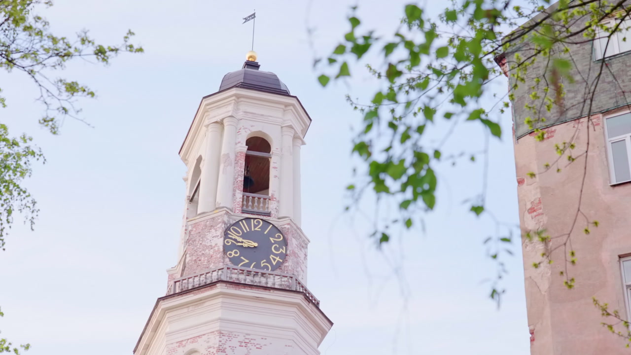 Clock Tower Framed By Leafy Branches, Pastel Facade With Ornate Balcony And Large Dial, Bell Visible In Open. Creative