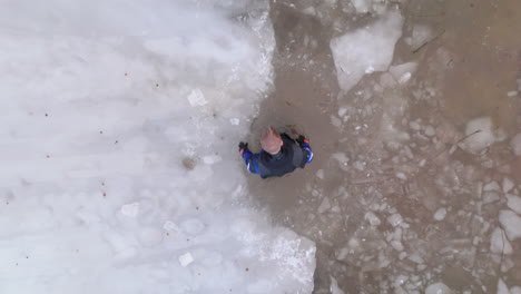 el buzo de hielo usa un hacha de hielo para romper el borde del hielo del lago para abrir el punto de entrada.