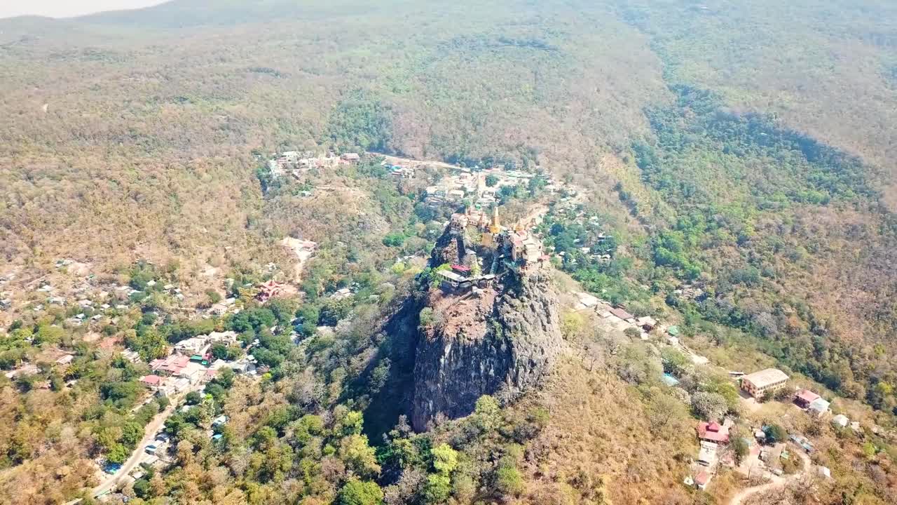 vista aérea del monte popa, un volcán extinto con el templo budista de nat en la parte superior, rodeado de vegetación seca y una aldea en la parte inferior, ubicado en la región de mandalay, en el centro de myanmar.