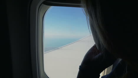 woman looking out the window in airplane