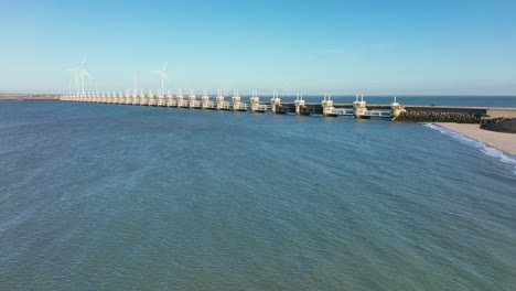 toma aérea en cámara lenta del mar del norte, la barrera contra la marejada ciclónica del este de scheldt y las turbinas eólicas en zelanda, los países bajos en un hermoso día soleado