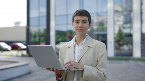 woman working on laptop outside modern building