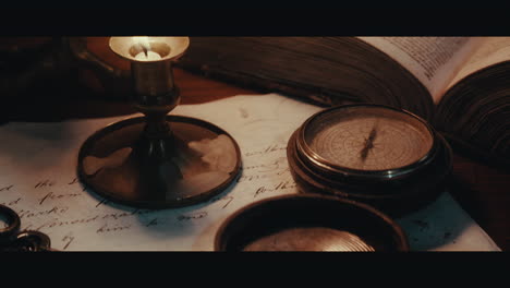 an old compass on the table filled with documents and maps inside the sailing ship cabin