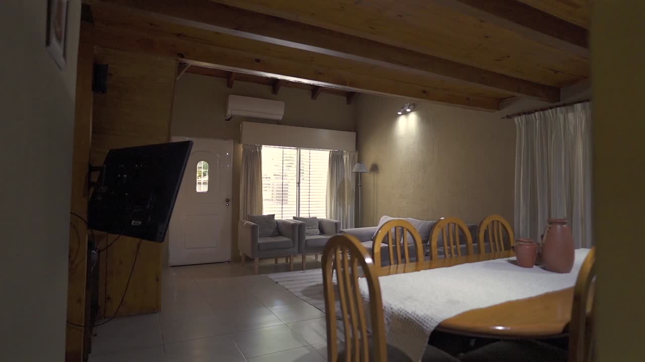 Corner clip highlights inviting open-concept space with seating area, large dining table, and rustic wood ceilings. Ideal for family rental listings.