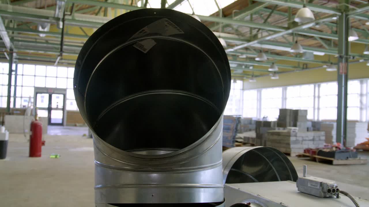 Metal ventilation duct for use at a construction site in a warehouse with video panning right to left.