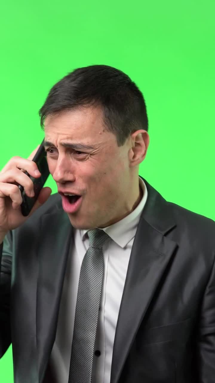Uomo d'affari che esprime diverse emozioni durante una telefonata su sfondo green screen