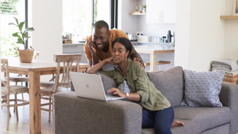 una joven pareja afroamericana usa una computadora portátil en el sofá en casa