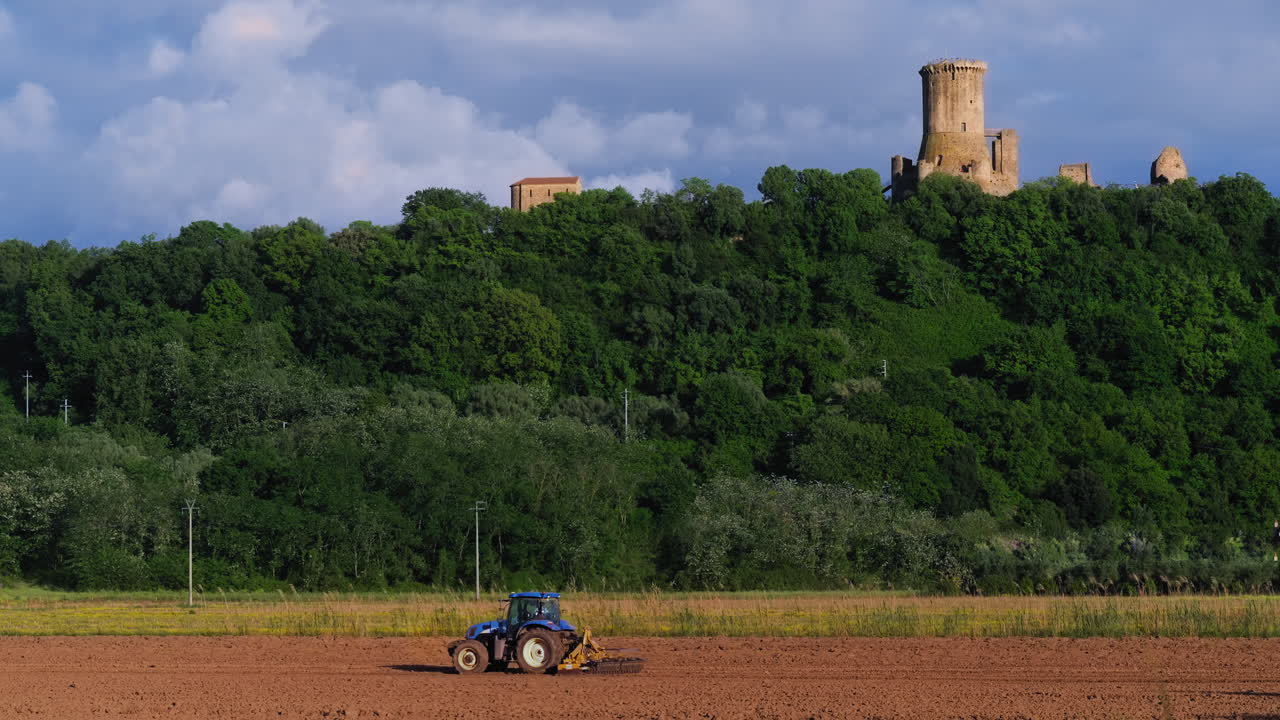 A tractor plowing a field under the ruins of the ancient tower of Velia (Elea) in Ascea