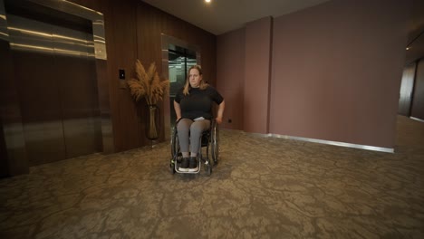 una mujer en silla de ruedas se acerca a un ascensor en el vestíbulo de un hotel, mostrando alojamientos accesibles y diseño moderno. la escena hace hincapié en la movilidad, la independencia y la inclusión en la hospitalidad.