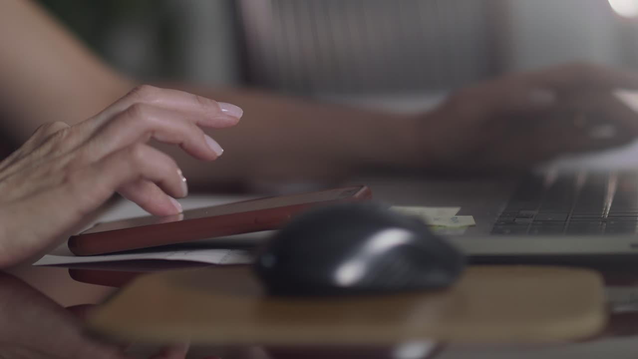 Mano femminile che digita sul suo smartphone, invia messaggi ed email ed esegue calcoli