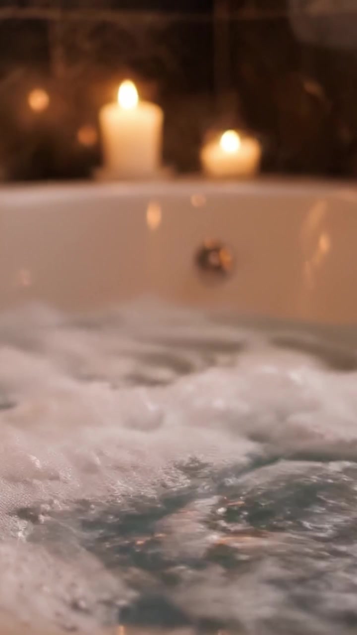 A Relaxing Bath Experience: Soothing Candles and Bubbling Water Create a Tranquil Atmosphere for Self-Care and Serenity in the Comfort of Home