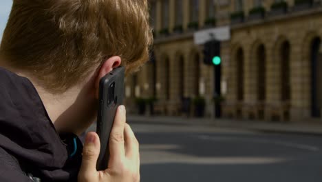 über-Die-Schulter-Geschossen-Von-Einem-Mann,-Der-Auf-Einer-Belebten-Straße-In-Oxford-Mit-Dem-Handy-Telefoniert?