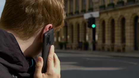 por encima del hombro, un hombre hablando por teléfono móvil en una calle concurrida de oxford