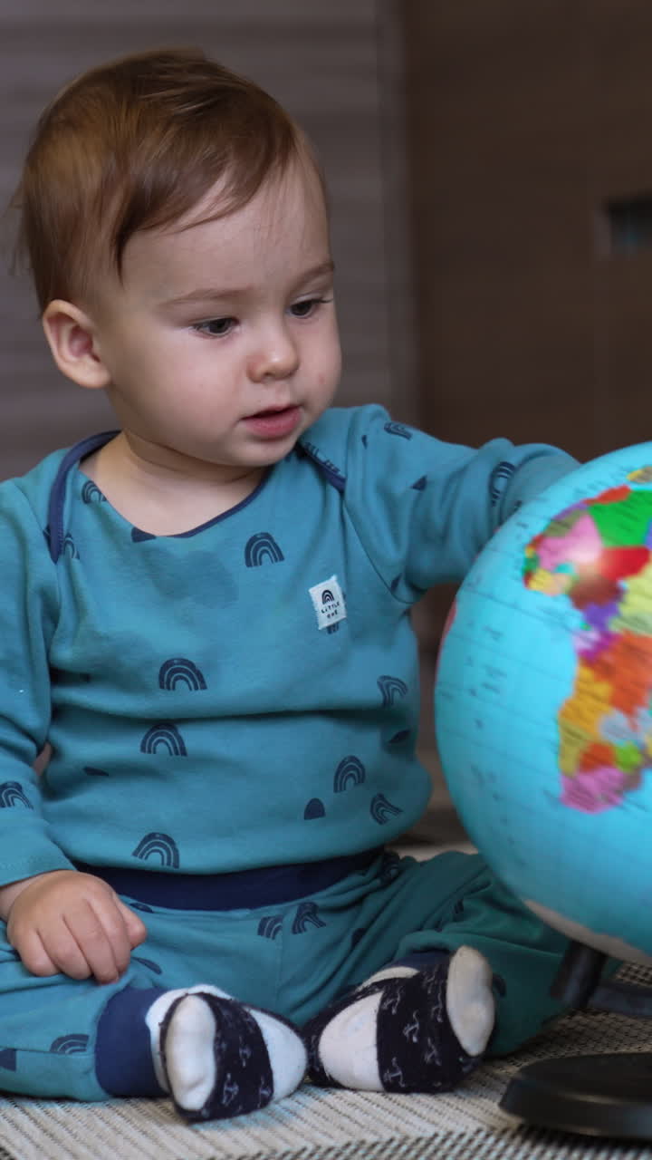 Small playful kid have fun with globe. Cute little boy playing with globe. Vertical video