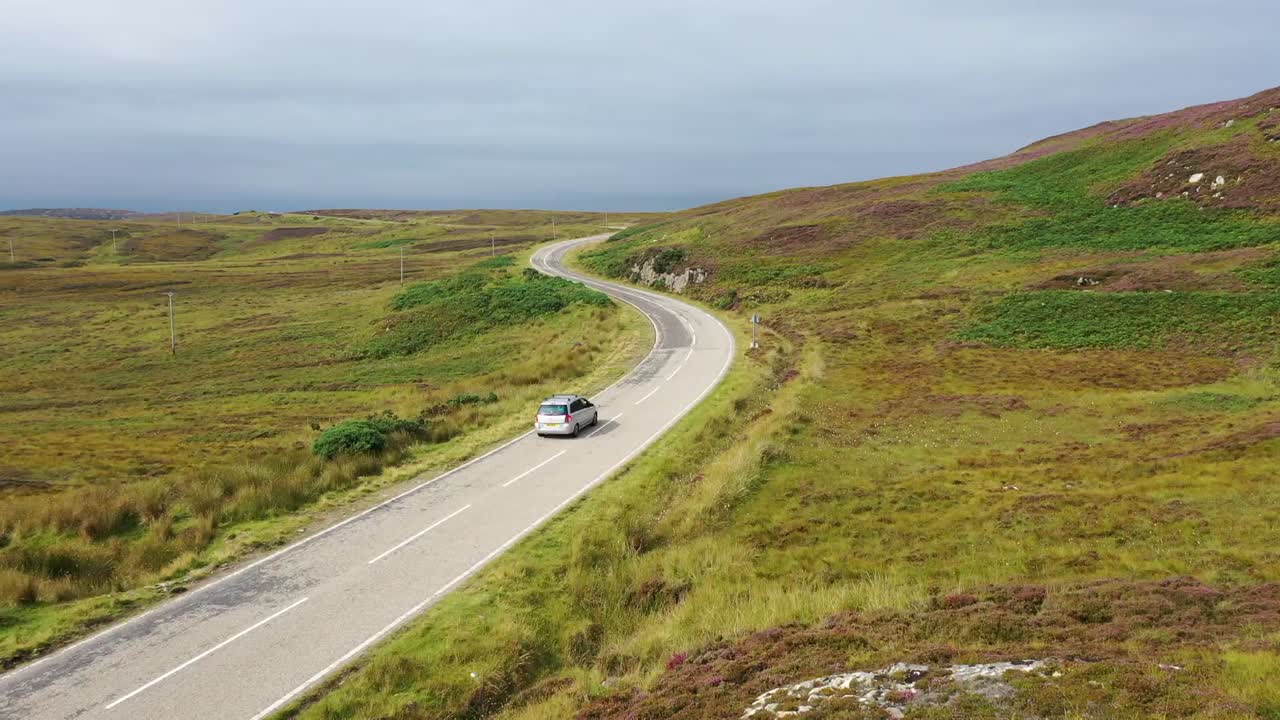 john'o'groates에서 무인 항공기가 도로 위로 확대되어 스코틀랜드 북부 해안의 광활한 광활함을 드러냅니다.