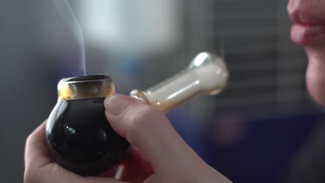 cerca de fumar pipa con marihuana medicinal sostenida por mano femenina