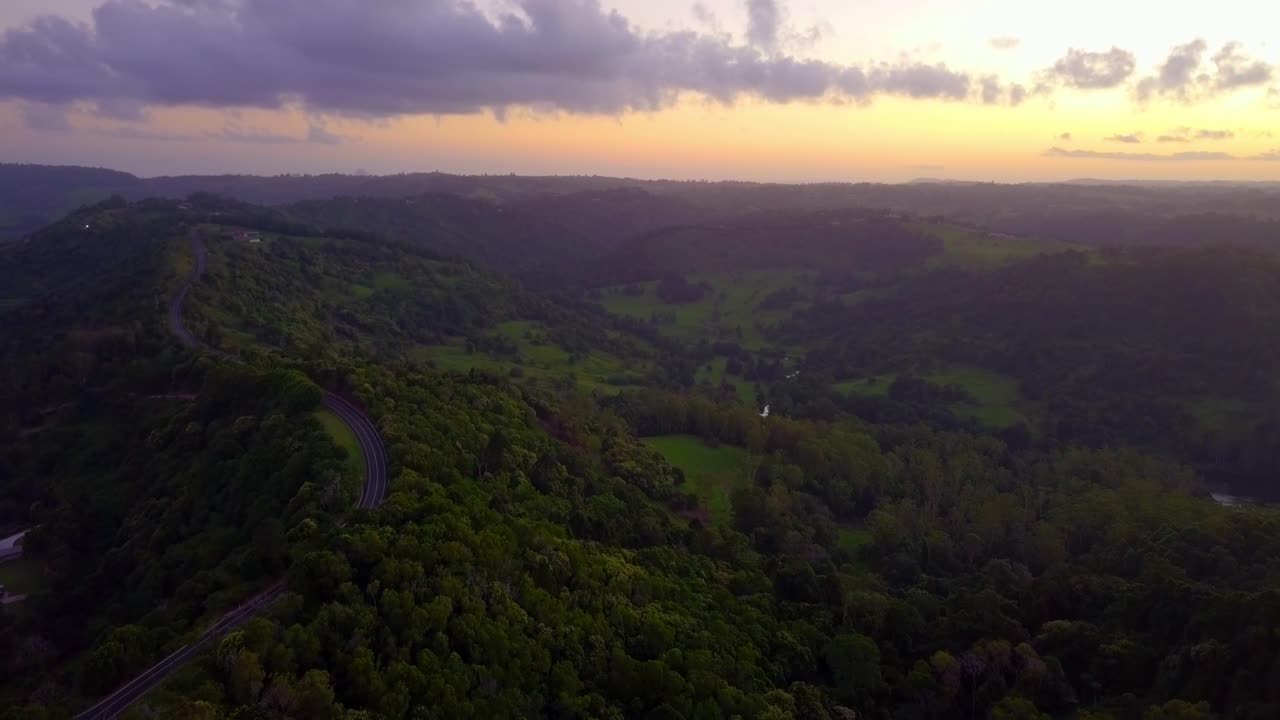 vista aérea de colinas y carreteras en un valle de bosque tropical al atardecer