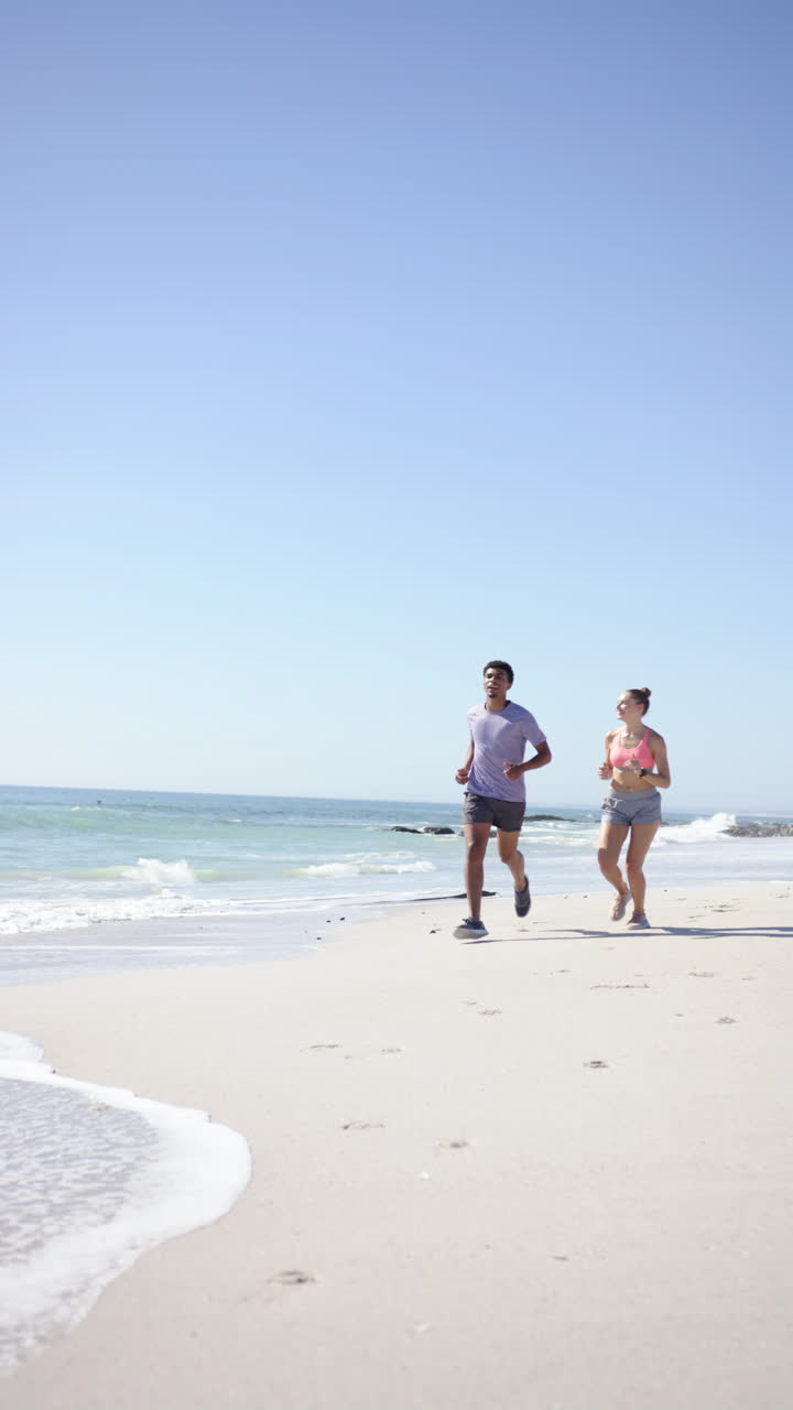 Vertical video: Running on beach, couple enjoying fitness activity together by ocean