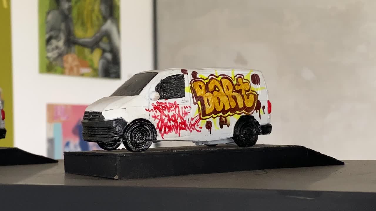 The footage shows the interior of a coffee shop displaying uniquely drawn miniature cars on the cupboard shelves.