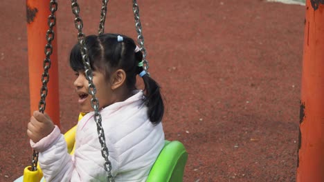 Kind-Vergnügt-Sich-Auf-Einer-Schaukel-Auf-Dem-Spielplatz-Im-öffentlichen-Park